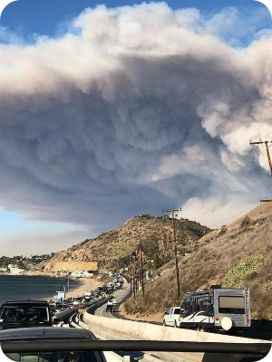 The smoke plume from the fast-moving Woolsey Fire encroaching on Malibu on November 9, 2018, as residents evacuate along the Pacific Coast Highway (PCH)